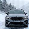 Auto mit Winterreifen und Schneeketten vor alpiner Winterlandschaft in Österreich